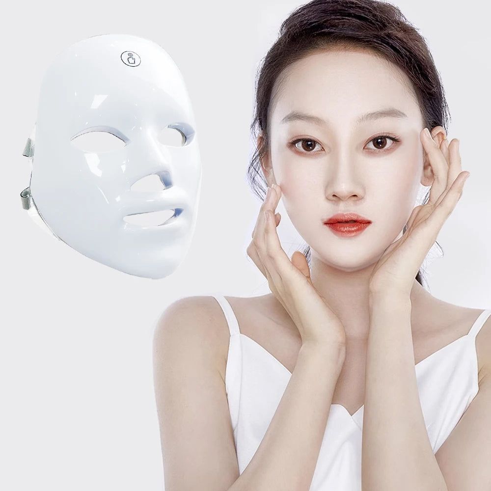 Woman holding a white LED face mask with a plain background
