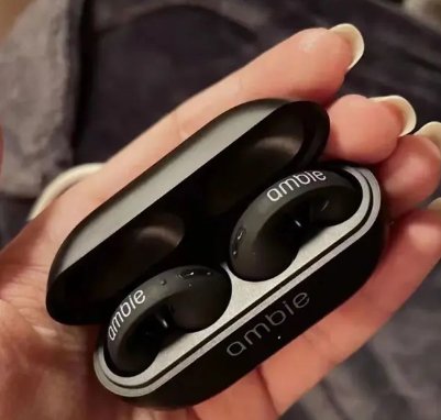 Black wireless earbuds in a charging case held by a hand